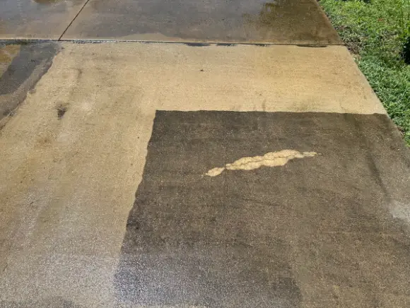 Concrete driveway mid-cleaning, showing clean versus stained surface