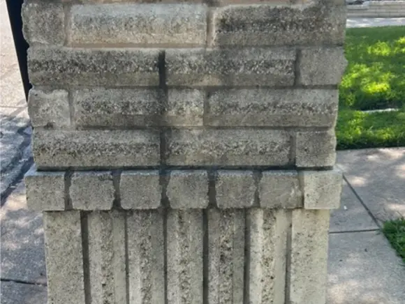Stone column before soft washing, streaked with mildew