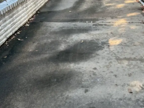 Side driveway before pressure washing, covered in dark stains